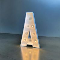 A - Letra de madera pintada en blanco con bombillas de decoración